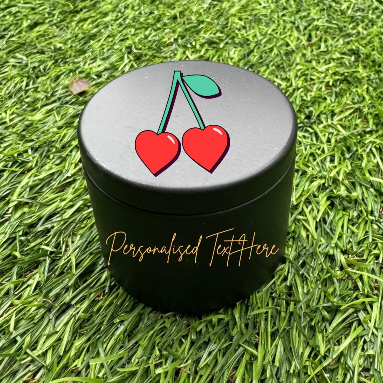 Black candle holder case with personalised text around the the cylinder and cherries shaped as a heart graphic on top of lid.