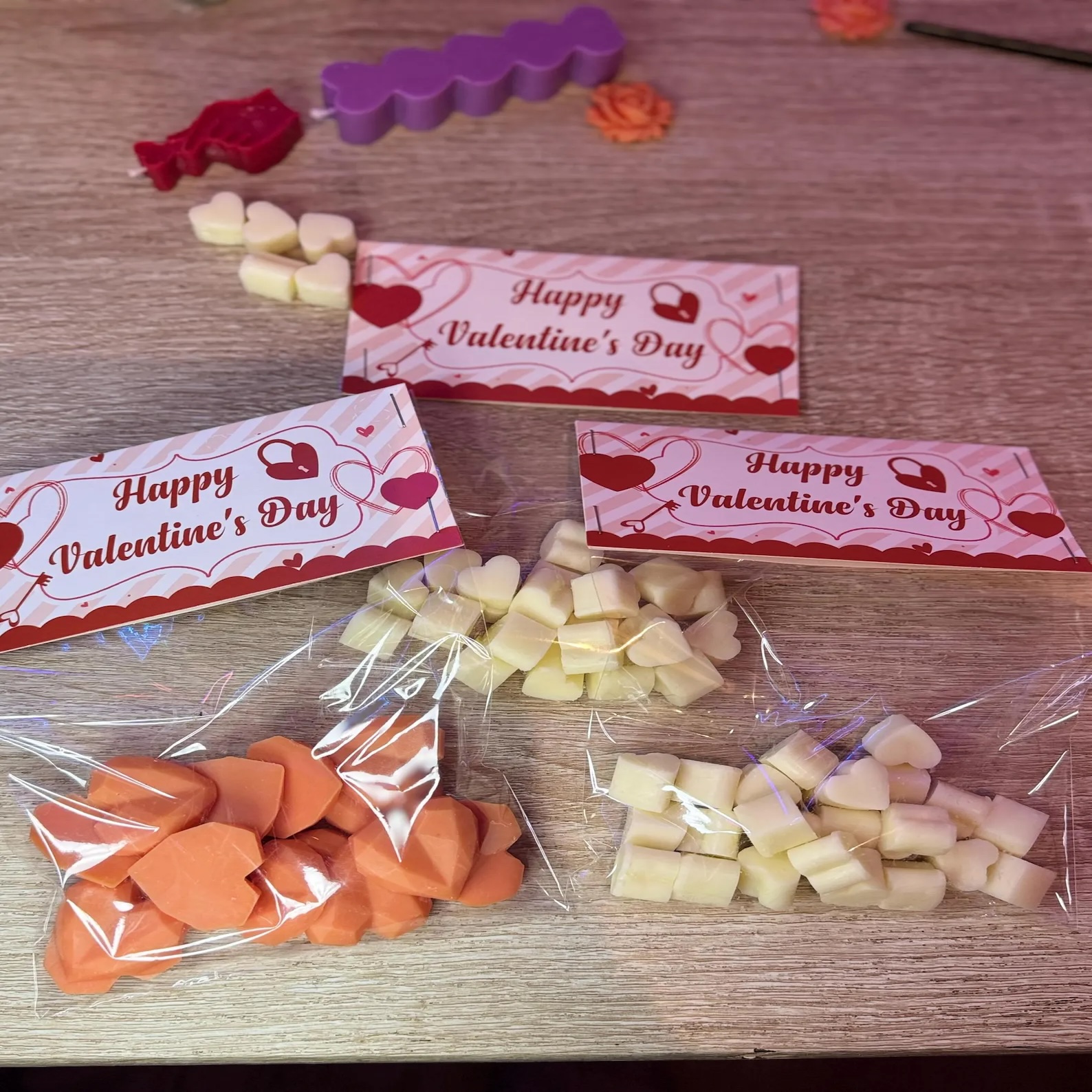 Three bags of heart-shaped wax melts in orange and cream with happy valentines packaging.
